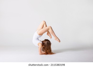 preteen girl gymnast trains on white background in white leotard. children's professional sports, rhythmic gymnastics. 