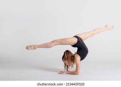 preteen girl gymnast trains on white background in black leotard. children's professional sports, rhythmic gymnastics