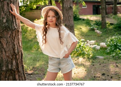 Preteen Girl Leaning Of Tall Tree Trunk In Green Courtyard Of Country House