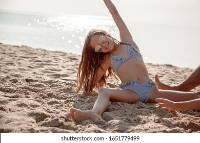 Preteen girl playing with sandy on the beach wearing swimsuit