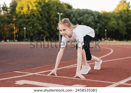 Pre-teen girl ready to race on an athletics track. Child girl on the starting line ready to run. Children sport, accomplishment , healthy active lifestyle concept.