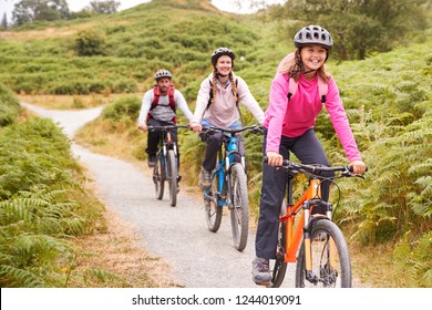 Pre-teen girl riding mountain bike with her parents during a family camping trip, close up - Powered by Shutterstock