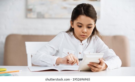 Preteen Girl Using Calculator Near Notebook And Stationery At Home