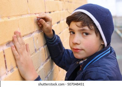 Preteen Handsome Boy In Blue Hat Drawing On The Wall Close Up Portrait