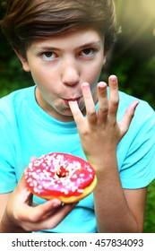 Preteen Handsome Boy Eat Doughnut With Strawberry Red Glaze Topping Lick His Fingers