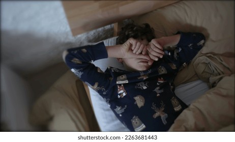 Preteen kid rubbing face and eyes laying in bed. Tired Young boy waking up - Powered by Shutterstock