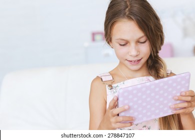 Preteen School Girl Of 8-9 Years Old Playing On Ipad Tablet Pc At Home