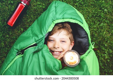 Preteen School Kid Boy In Sleeping Bag Camping. Outdoors Activity With Children In Summer. Fun And Adventure Camp, Family And Friends Vacations Or Weekend Trip. Portrait Of Child With Flashlight.