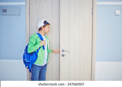 Pre-teen Schoolboy Opening Classroom Door And Looking Inside