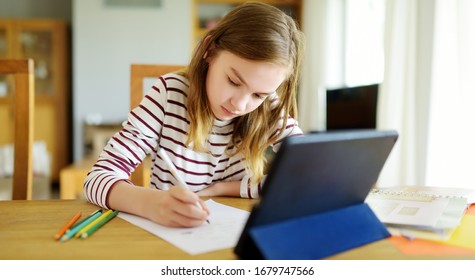 Preteen Schoolgirl Doing Her Homework With Digital Tablet At Home. Child Using Gadgets To Study. Education And Distance Learning For Kids. Homeschooling During Quarantine. Stay At Home Entertainment.