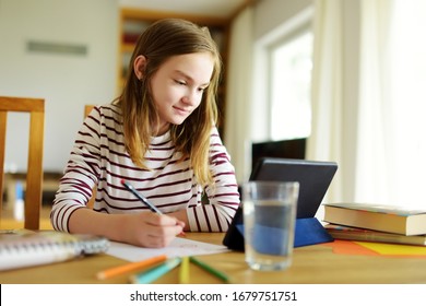 Preteen schoolgirl doing her homework with digital tablet at home. Child using gadgets to study. Education and distance learning for kids. Homeschooling during quarantine. Stay at home entertainment. - Powered by Shutterstock