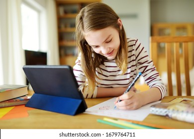 Preteen Schoolgirl Doing Her Homework With Digital Tablet At Home. Child Using Gadgets To Study. Education And Distance Learning For Kids. Homeschooling During Quarantine. Stay At Home Entertainment.