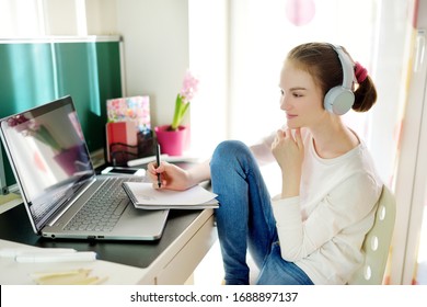 Preteen schoolgirl doing her homework with laptop computer at home. Child using gadgets to study. Online education and distance learning for kids. Homeschooling during quarantine. Stay at home.