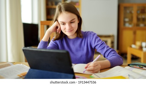 Preteen schoolgirl doing her homework with digital tablet at home. Child using gadgets to study. Education and distance learning for kids. Homeschooling during quarantine. Stay at home entertainment.