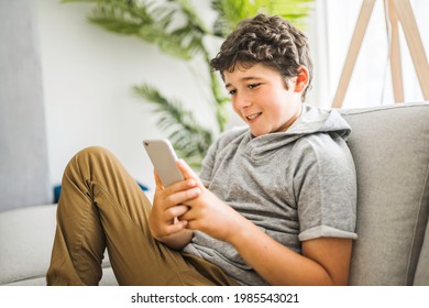 A Pre-teen sit on the couch using smartphone and look sad and boring - Powered by Shutterstock