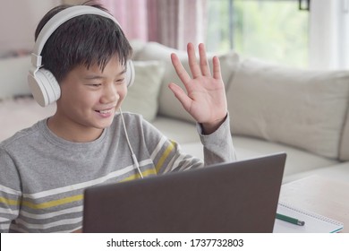 Preteen tween teen Asian boy making facetime video calling with laptop at home, using zoom  online virtual class , social distancing ,homeschooling,learning remotely during covid coronavirus pandemic
