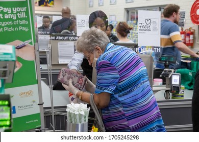 Pretoria, Gauteng, South Africa - 04 14 2020, Old Woman At Grocery Store Counter Paying With Mask Out Of Focus And With Grain