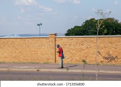 Pretoria, Gauteng, South Africa, April 24 2020, Man Next To The Road During Corona Virus Lockdown Covid-19 Pandemic Looking At Phone Out Of Focus And With Grain