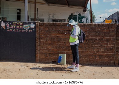 Pretoria, Gauteng, South Africa, April 24 2020, Worker Standing Looking At Phone In Front Of Brick Wall