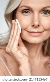 Pretty 50s middle aged old woman holding cotton pad sponge cleansing face skin purifying with cleanser, happy mature lady removing makeup enjoy healthy clean anti age dry skincare lifting routine. - Shutterstock ID 2147155467