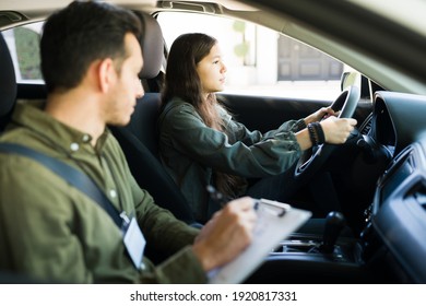 Pretty adolescent girl driving a car with the seatbelt. Male instructor telling some instructions and directions to a teen girl during a lesson - Powered by Shutterstock