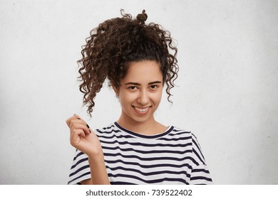 Pretty Adorable Young Female With Curly Pony Tail Has Shy Expression As Looks At Handsome Stylish Guy, Feels Embarrassed. Smiling Beautiful Woman Being Proud Of Her Great Success And Victory