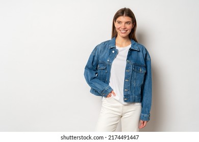 Pretty adorable youthful woman with fair hair dressed in white t-shirt, denim jacket and jeans, holding hand in pocket, smiling against blank studio wall with copy space. Fashion and trends concept - Powered by Shutterstock