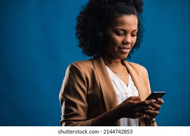 Pretty Adult Woman, Checking Her Phone Log, While Standing In A Blue Background Room.