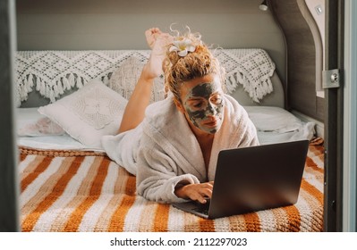 Pretty Adult Woman With Skin Beauty Cream On Face Work On Laptop Computer Laying In Camper Van Bedroom. Travel Lifestyle Female People With Online Job. Modern Lady And Healthy Treatment