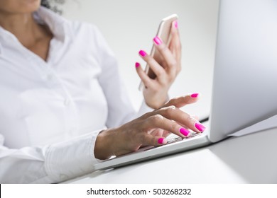 Pretty African American Woman's Hands And Torso. She Is Holding Her Cell Phone And Typing At Laptop Keyboard. 