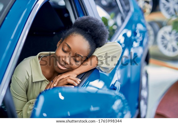 pretty african lady\
liked automobile in cars showroom, going to buy it, sit inside of\
it, leaned on window