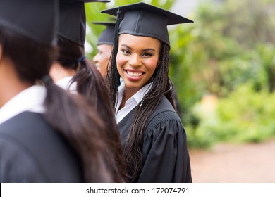pretty african university graduate looking back at graduation ceremony