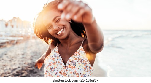 Pretty African Woman Having Fun At The Beach - Happy Female Enjoying Vacation By The Seaside - Body Care, Wellness, Travel And Mental Health Concept