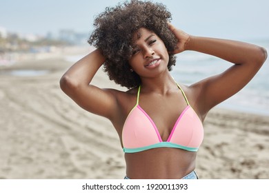 Hübsche Afro-Amerikanerin mit Händen über Kopf am Strand