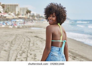 Pretty afro american woman turning around on beach laughing
