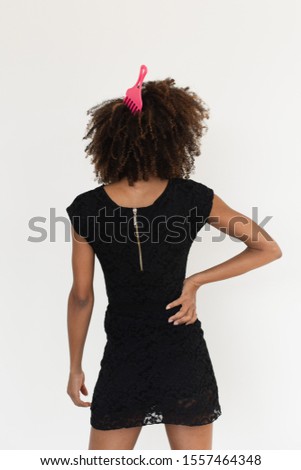Pretty afro hairstyle woman using comb for untangle her curly hair. Black female beauty and style tips concept.