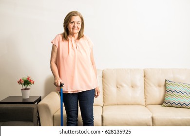 Pretty aged granny using a blue cane to stand up comfortably and walk at home - Powered by Shutterstock