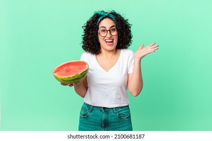 pretty arab woman feeling happy and astonished at something unbelievable and holding a watermelon. summer concept