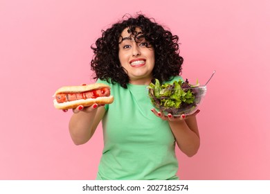 pretty arab woman holding a salad and a hot dog. diet concept