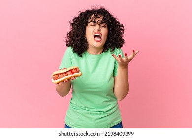 Pretty Arab Woman Looking Angry, Annoyed And Frustrated And Holding A Hot Dog