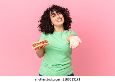 pretty arab woman smiling happily with friendly and  offering and showing a concept and holding a hot dog
