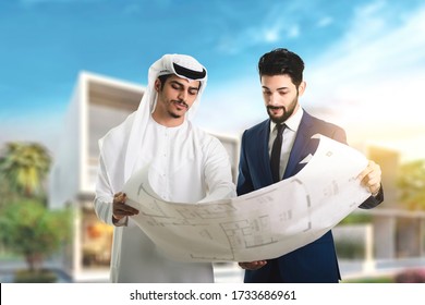 Pretty architect is explaining to Arab builders the plan of construction. The foreman pointing at building with seriousness.