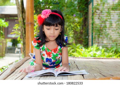 Pretty Asian Child Reading Book In Wood Cottage