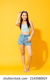 Pretty Asian female model wearing summer outfit posing in studio yellow isolated background