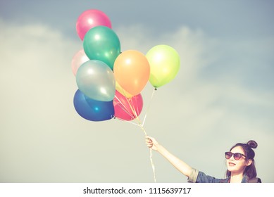 Pretty Asian girl hand holding colorful balloons on blue sky background for birthday, wedding honeymoon and cerebration party in vintage retro style.