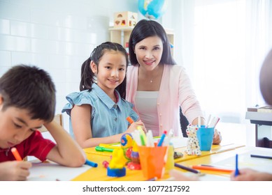 Pretty asian girl and teacher smiling in art classroom - Shutterstock ID 1077217592