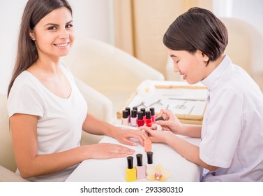 Pretty Asian Manicurist Applying Nail Polish To Client. Hands Care Concept.