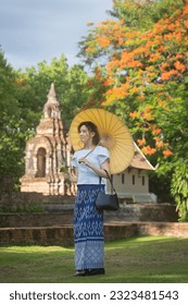 Pretty Asian tourists woman wearing beautiful hand-woven clothes dyed with indigo and mud-fermented natural colors modern Thai traditional dress costumes are popular in the ancient temple in Thailand. - Shutterstock ID 2323481543