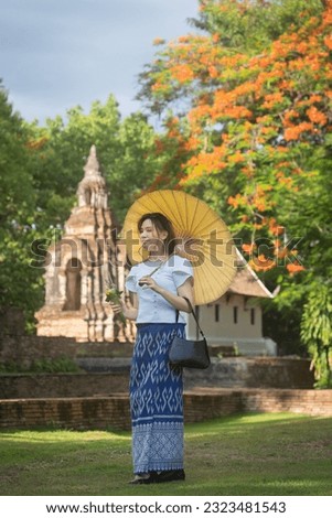 Pretty Asian tourists woman wearing beautiful hand-woven clothes dyed with indigo and mud-fermented natural colors modern Thai traditional dress costumes are popular in the ancient temple in Thailand.