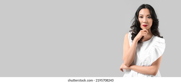 Pretty Asian Woman With Beautiful Wavy Hair On Grey Background With Space For Text